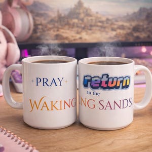 Puede incluir: Dos tazas de café blancas humeantes, llenas de líquido oscuro. Una taza dice "PRAY WAKING" en azul y naranja. La otra taza dice "return to the NG SANDS" en texto pixelado. Las tazas están sobre una superficie de madera.