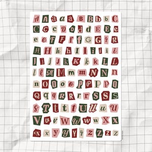 May include: A collection of cut-out letters in green, pink, and burgundy, arranged on a sheet of paper. The letters are in various fonts and sizes, including both uppercase and lowercase. The background is a grid pattern.