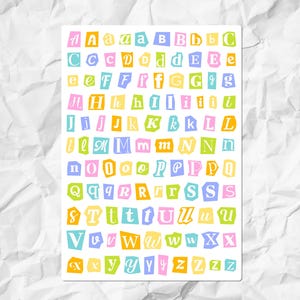 May include: A sticker sheet featuring the full alphabet in both uppercase and lowercase letters. Each letter is printed on an individual, irregularly shaped, torn-paper style background in various pastel colours including pink, yellow, blue, and green.