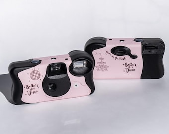 May include: Two disposable cameras with a light pink and black colour scheme. The cameras feature the text Bella's Hens Disco, a disco ball graphic, a champagne tower illustration, and the text 3rd of August 2024 and Turn on the flash.