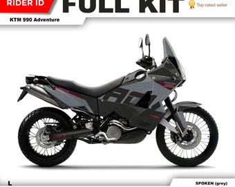 May include: A black and gray motorcycle with a custom graphic design. The design features a black and gray camouflage pattern with red accents. The motorcycle is a KTM 990 Adventure.
