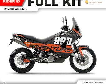 May include: A black and orange motorcycle graphic kit for a KTM 990 Adventure motorcycle. The kit features the words "Ready to Race" and "Adventure" along with the number "990".