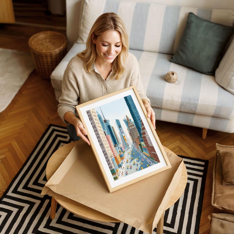 K&ouml;nnte beinhalten: Ein gerahmter Kunstdruck, der eine Stadtstra&szlig;enszene mit hohen Geb&auml;uden und gelben Taxis zeigt. Das Kunstwerk befindet sich in einem hellen Holzrahmen. Der Druck liegt auf einem runden Tisch mit einem schwarz-wei&szlig; gemusterten Teppich.