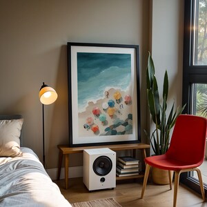 May include: A framed watercolor print of a beach scene with colorful umbrellas hangs above a small wooden bench. A white speaker sits below the print. A red chair and a floor lamp are also in the room.