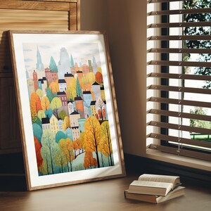 May include: A framed print of a colorful illustration of a city skyline with buildings and trees. The buildings are in various shades of blue, green, yellow, and red. The trees are in shades of green, yellow, and orange. The print is framed in a light brown wood frame.