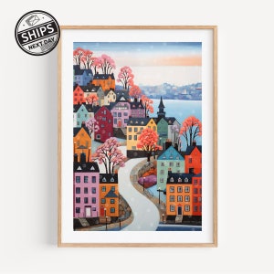 May include: A colorful painting of a town with houses in various shades of pink, blue, green, yellow, and red. The houses are clustered together on a hillside with a winding road leading down to a body of water. There are trees with pink blossoms in the foreground.