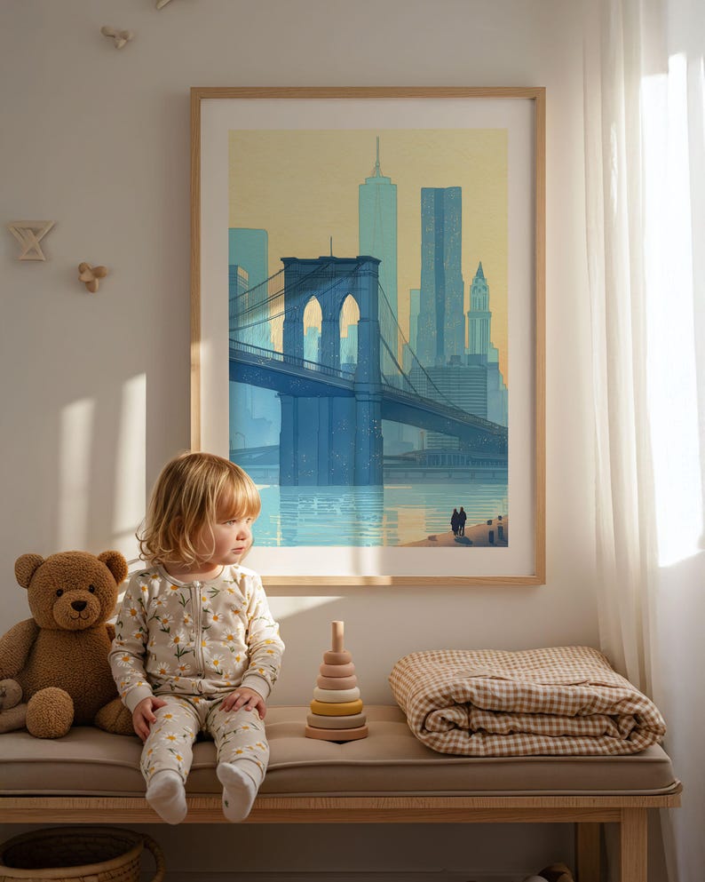 Puede incluir: Una impresi&oacute;n enmarcada del puente de Brooklyn en tonos azules y amarillos cuelga sobre un banco. Un ni&ntilde;o con un mono floral est&aacute; sentado en el banco junto a un oso de peluche, un juguete apilable de madera y una manta doblada.