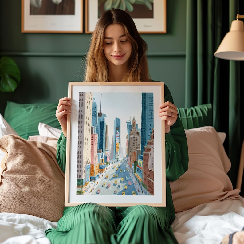 K&ouml;nnte beinhalten: Ein gerahmtes Aquarellgem&auml;lde einer Stadtstra&szlig;enszene mit hohen Geb&auml;uden und gelben Taxis. Das Kunstwerk befindet sich in einem hellen Holzrahmen. Das Gem&auml;lde zeigt eine lebendige Stadtlandschaft mit farbenfrohen Geb&auml;uden und einer belebten Stra&szlig;e.