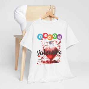 May include: White t-shirt with a red heart and the text "Bingo is my Valentine" with colorful bingo balls spelling out "Bingo" above the heart.