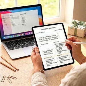 May include: A digital tablet displaying a Daily Clarity Dashboard with handwritten notes, held by hands using a white stylus. A laptop with a productivity app open sits nearby, alongside two wooden pencils, three metal paper clips, and a gift box.