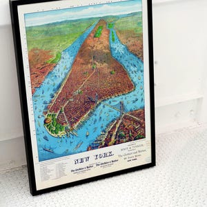 May include: Framed vintage map of New York City, featuring a detailed aerial view with a black frame. The map showcases the city's layout, including waterways, bridges, and buildings. The text "NEW YORK" is visible at the bottom.