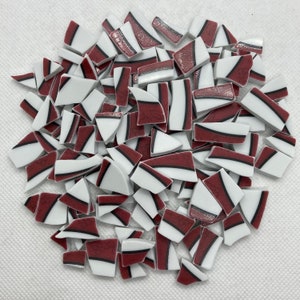 May include: A collection of mosaic tiles in various shapes. The tiles feature a combination of white, burgundy, and black colors. The burgundy sections have a textured appearance, while the white sections are smooth. The tiles are suitable for mosaic art projects.