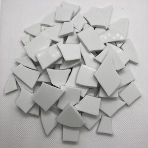 May include: A pile of white ceramic tile pieces in various shapes and sizes. The tiles are smooth and glossy.