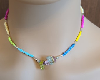 Puede incluir: Un collar de cuentas de colores con una cadena de plata y un grupo de piedras preciosas multicolores en el centro.