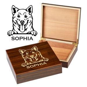 May include: A wooden box with a hinged lid. The box is engraved with a black and white illustration of a dog's head peeking over the top of the box. The dog's name, "Sophia", is engraved in gold lettering below the illustration.