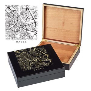 May include: A black wooden box with a gold map of Basel on the lid. The box is open and the inside is lined with wood.