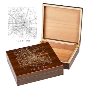 May include: A wooden box with a hinged lid. The top of the box is engraved with a map of Houston, Texas. The lid is open and the inside of the box is lined with wood.