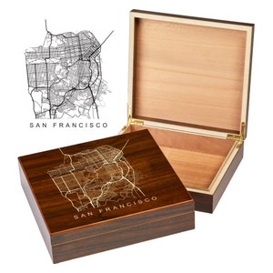 May include: A wooden box with a hinged lid. The lid is open and the inside of the box is lined with wood. The top of the box is decorated with a gold-colored map of San Francisco.
