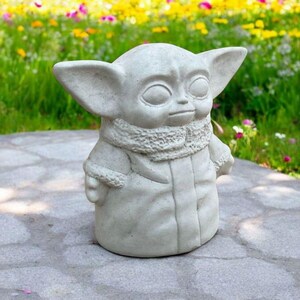 Pu&ograve; includere: Una statua di cemento grigio di un personaggio immaginario con grandi orecchie e un colletto di pelliccia. La statua &egrave; in piedi su un sentiero di pietra grigia.