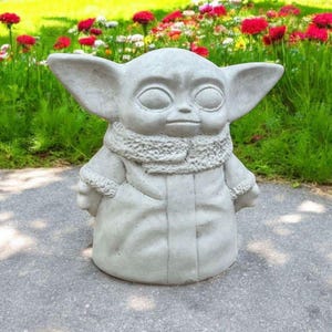 Pu&ograve; includere: Una statua in ceramica bianca di un personaggio immaginario del franchise di Star Wars. Il personaggio indossa una tunica con cappuccio e ha grandi orecchie.