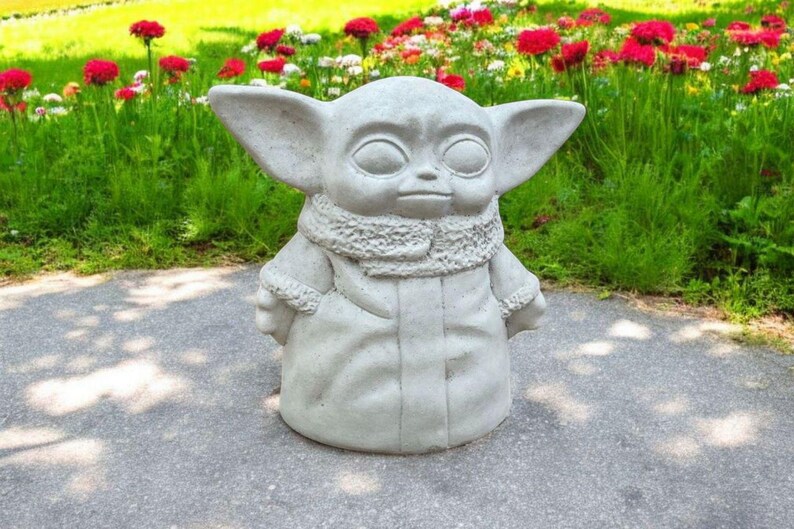 Pu&ograve; includere: Una statua in ceramica bianca di un personaggio immaginario del franchise di Star Wars. Il personaggio indossa una tunica con cappuccio e ha grandi orecchie.