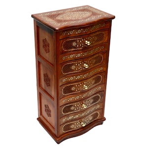 Puede incluir: Un joyero de madera con siete cajones. El cofre es de color marrón intenso con intrincados diseños florales incrustados en un color más claro. Los cajones tienen frentes curvos y pomos de color latón. La parte superior del cofre también presenta diseños incrustados.