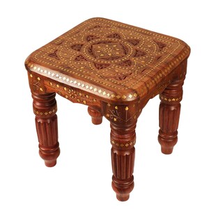 May include: A square, wooden footstool with intricate floral carvings and brass inlay. The dark brown stool has four turned legs and measures approximately 30 cm in height and 30 cm in width.