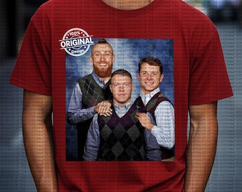 Op de afbeelding: Rood t-shirt met een groepsfoto van drie mannen in argyle vesten over overhemden. De afbeelding is omlijst door een witte cirkel met de tekst "100% ORIGINAL Design".