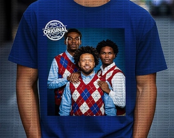 Op de afbeelding: Koning blauw t-shirt met een afbeelding van drie mannen in argyle vesten en overhemden met knopen. De afbeelding bevat de tekst "100% Original Design" in een cirkelvormige badge. Het ontwerp is gecentreerd.