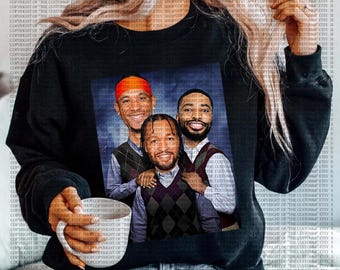 Op de afbeelding: Zwarte crewneck sweatshirt met een afbeelding van drie lachende mannen in argyle vesten en overhemden met kraag. Eén man draagt een rode hoofdband. De afbeelding heeft een blauwe achtergrond.