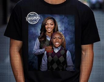 Op de afbeelding: Zwart T-shirt met een portret van twee lachende vrouwen in ruitjesvesten over overhemden met kraag, tegen een blauwe achtergrond. Een cirkelvormige afbeelding linksboven leest "100% ORIGINAL Design."
