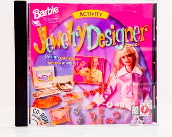 May include: A pink CD-ROM case with a Barbie Software Girls logo and the title "Jewelry Designer" in a colorful font. The case features a picture of a Barbie doll wearing a pink shirt and a necklace. The text "Design and make your own real jewelry!" is printed on the case. The case also includes a rating of "E for Everyone" from the Entertainment Software Rating Board.