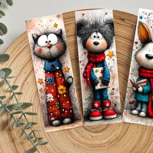 May include: Three illustrated bookmarks with cartoon characters. A grey cat in a blue top and red trousers with flowers. A bear in a red scarf and blue outfit. A dog with a red scarf and a book. Each bookmark is unique.