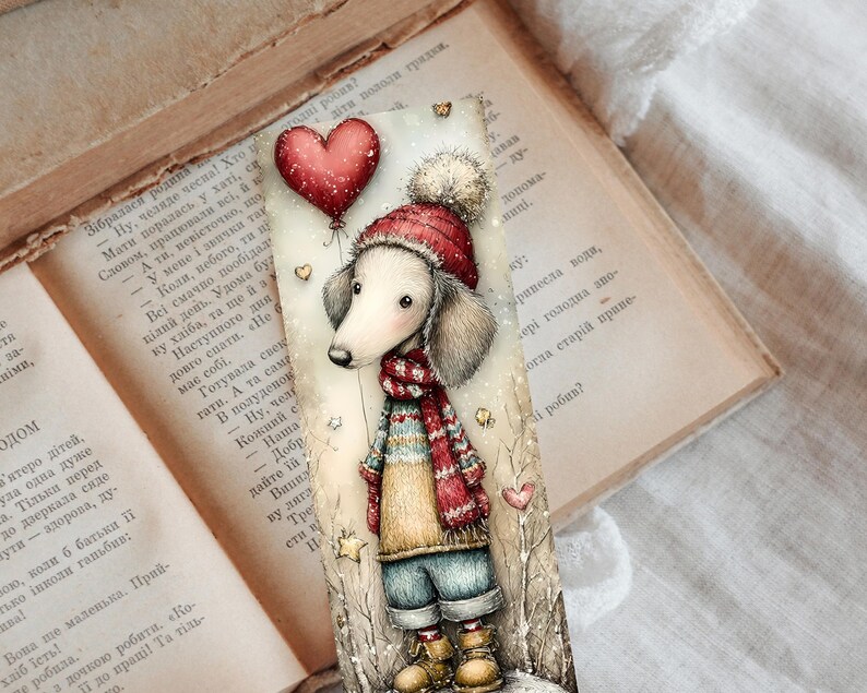May include: A whimsical bookmark featuring a dachshund wearing a red hat and scarf, holding a heart-shaped balloon. The illustration has a winter theme with a soft, muted color palette and a vintage book background.