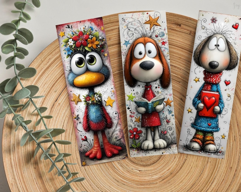 May include: Three whimsical bookmarks. One depicts a blue bird with a floral crown, another a brown dog reading a book, and the last a dog holding a heart-shaped book. Each bookmark has a unique design with vibrant colours.