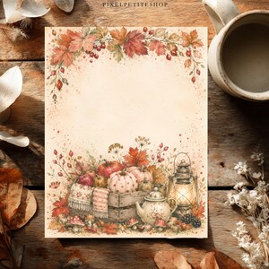 Op de afbeelding: Een rechthoekig vel briefpapier met een aquarelillustratie van herfstbladeren en bessen aan de bovenkant. De onderkant toont een houten kist gevuld met pompoenen, een theepot en een brandende lantaarn, omringd door herfstbladeren en bessen.