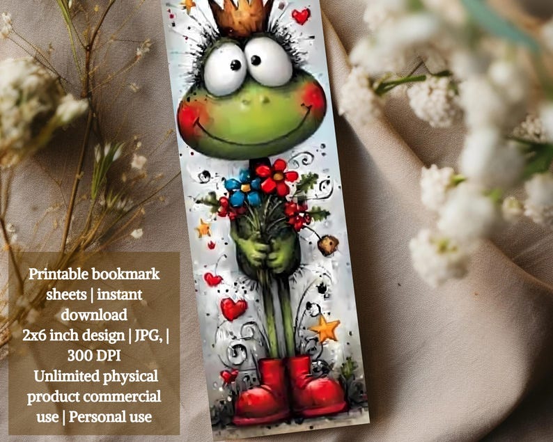 May include: A colourful bookmark with a cartoon frog wearing a crown and red boots, holding flowers. The design includes hearts and stars. The bookmark measures approximately 5 x 15 cm.