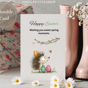 Pode incluir: Um cart&atilde;o de P&aacute;scoa imprim&iacute;vel com uma ilustra&ccedil;&atilde;o em aquarela de um ouri&ccedil;o, dois ovos decorados e uma borboleta. O cart&atilde;o diz "Feliz P&aacute;scoa" e "Wishing you sweet spring moments."