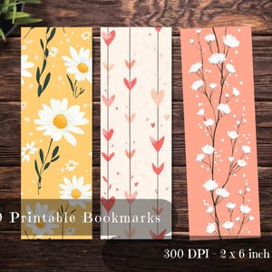 May include: Three printable bookmarks with floral and heart designs. One bookmark features daisies on a yellow background, another has red hearts on a cream background, and the third has white flowers on a peach background. The text reads "20 Printable Bookmarks" and "300 DPI - 2 x 6 inch".