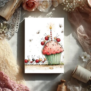 May include: A whimsical birthday card featuring a large pink cupcake with a lit candle. Ladybug-like creatures and ants surround the cupcake, with additional insects scattered around. The card has a watercolor style and a light green cupcake wrapper.