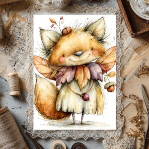 May include: A watercolor illustration of a fox character with large ears, rosy cheeks, and a bushy tail. The fox wears a collar made of autumn leaves in shades of orange, brown, and purple, and holds a small acorn-like fruit on a thin string.