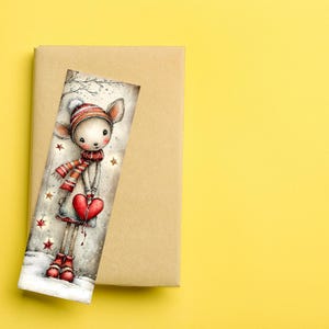 May include: A whimsical bookmark featuring a deer-like character in winter attire, holding a red heart. The character wears a striped hat and scarf, with red boots. The bookmark is set against a neutral background, with a yellow backdrop.