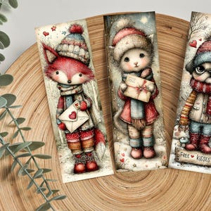 May include: Three whimsical bookmarks featuring winter-themed animal characters. A fox, cat, and pug are depicted in cozy winter attire, holding letters or wearing scarves. The pug bookmark has the text "FREE KISSES" on a small wooden sign.