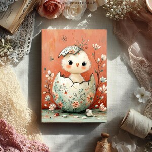 May include: An illustrated print featuring a baby chick hatching from an egg. The egg is decorated with floral patterns in shades of pink, blue, and green. The background is a soft coral color, and the overall style is whimsical and charming.