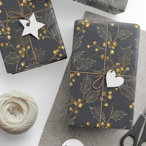 May include: Wrapped gifts with a dark gray background and a gold holly leaf and berry pattern. Each gift is tied with twine and has a white tag. A ball of twine, scissors, and a gray cloth are also in the image.