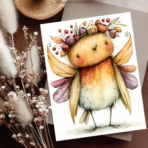 May include: A watercolor illustration of a small, round bird with yellow and orange feathers, wearing a crown of autumn berries and leaves. The bird has small wings, thin legs, and a soft, speckled texture. The text PIXELPETITESHOP is visible.