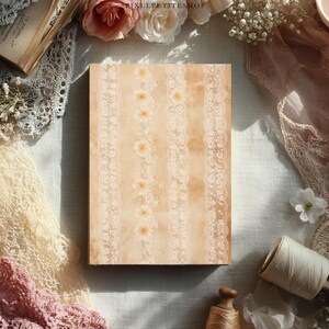 May include: A rectangular journal with a beige cover featuring vertical lace and floral patterns. The journal is surrounded by vintage-style lace, flowers, and a spool of thread, creating a romantic, antique aesthetic.