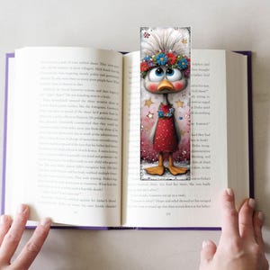 May include: A decorative bookmark with a cartoon duck wearing a floral crown and a red dress, inserted into an open book. The duck has large blue eyes and is surrounded by stars. A charming addition to any book.
