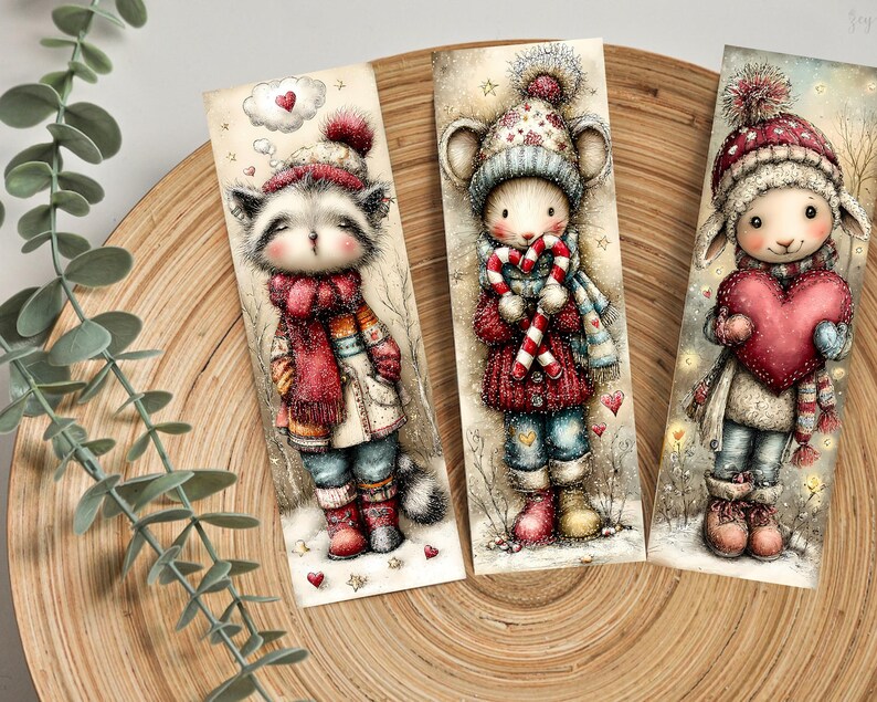 May include: Three illustrated bookmarks featuring adorable winter animals. The raccoon wears a red scarf and hat, the mouse holds a candy cane, and the lamb holds a heart. Each bookmark is set against a snowy background with hearts.