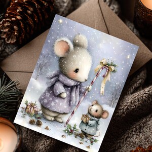 Puede incluir: Una tarjeta de Navidad con dos adorables ratones en una escena invernal nevada. Un rat&oacute;n lleva un abrigo y una bufanda morados, sosteniendo un bast&oacute;n de caramelo. El otro rat&oacute;n lleva un abrigo azul y sostiene un regalo. La tarjeta tiene un dise&ntilde;o caprichoso y festivo.